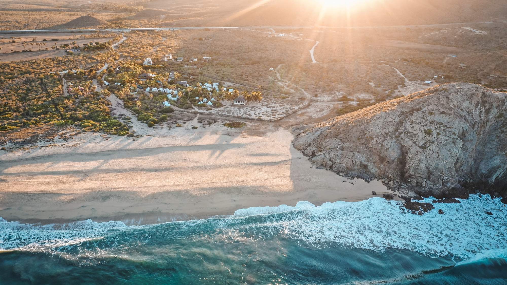 Aerial view of the retreat beach at sunrise, waves meeting the desert coastline