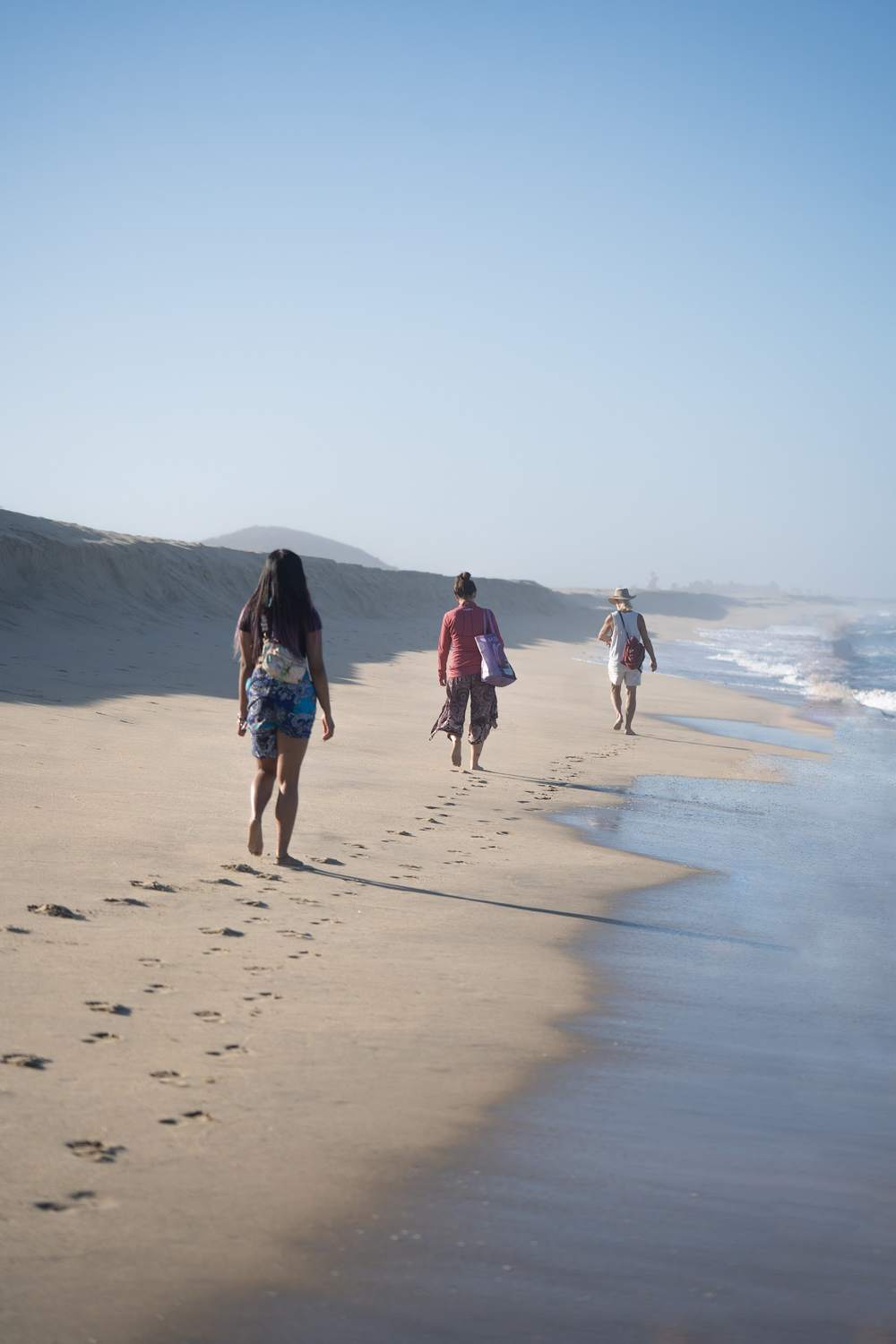 Three people walking along a quiet, misty beach